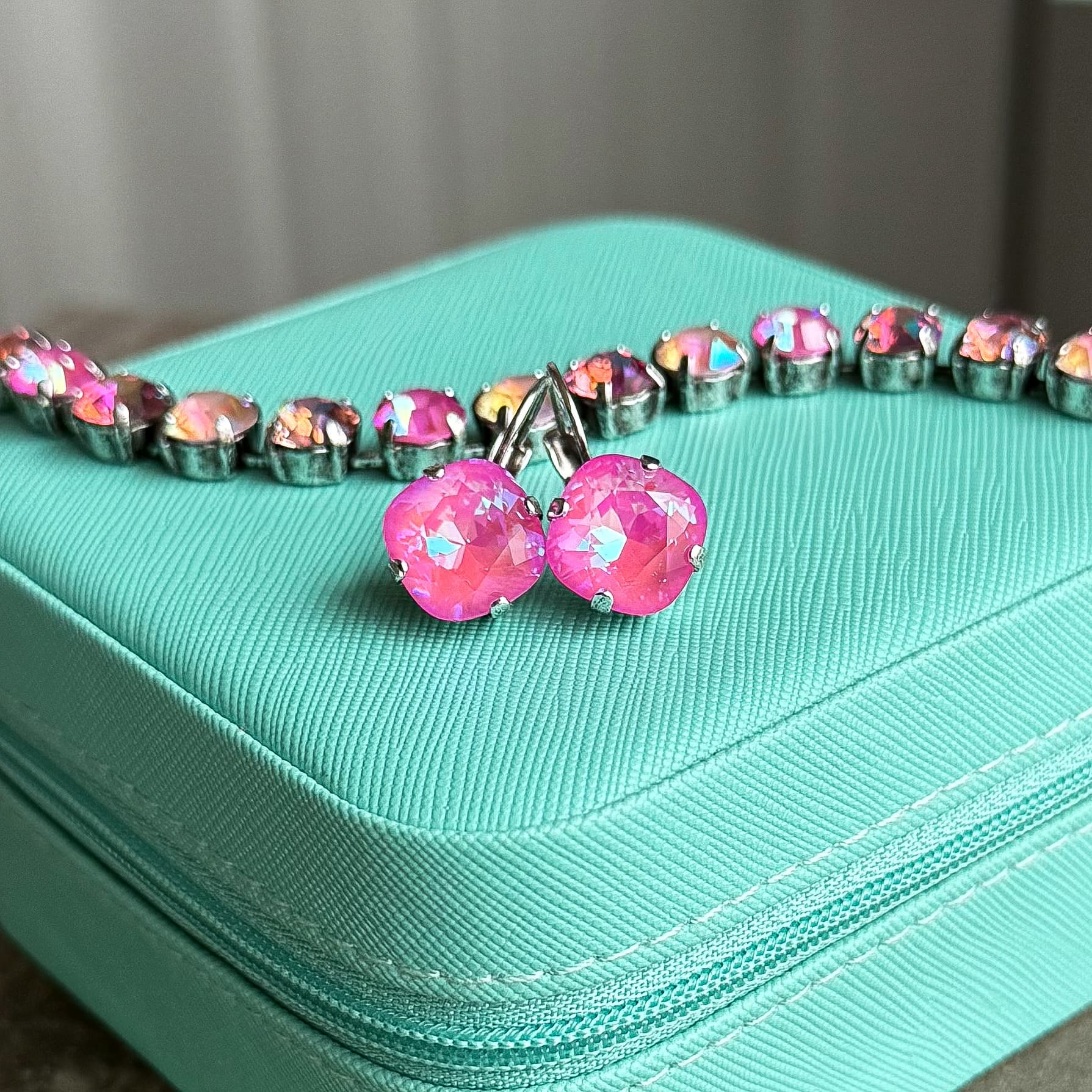 Hot pink Swarovski crystal lever-back earrings and matching necklace on teal jewelry box