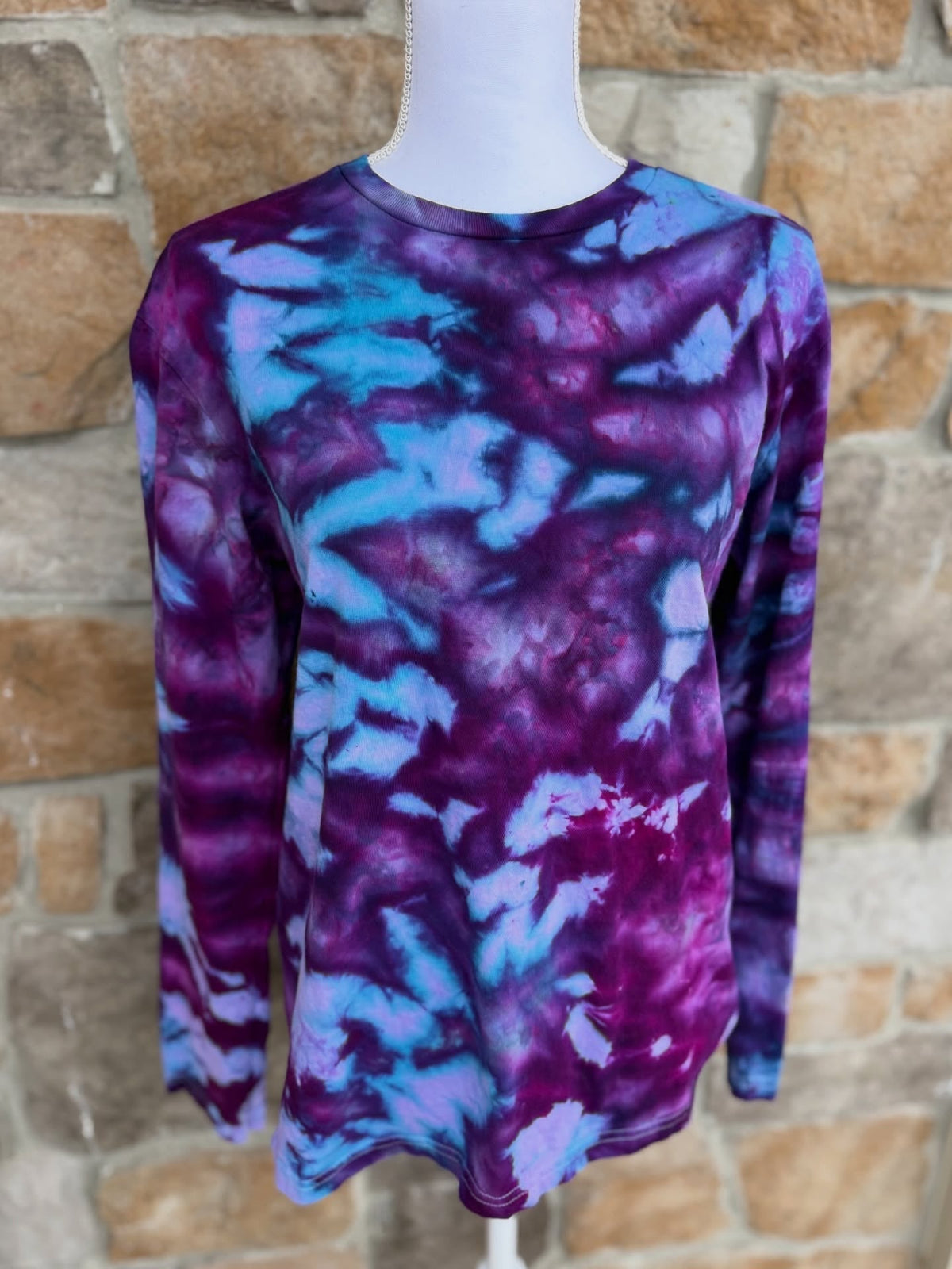 Ice dyed crewneck on mannequin against stone wall