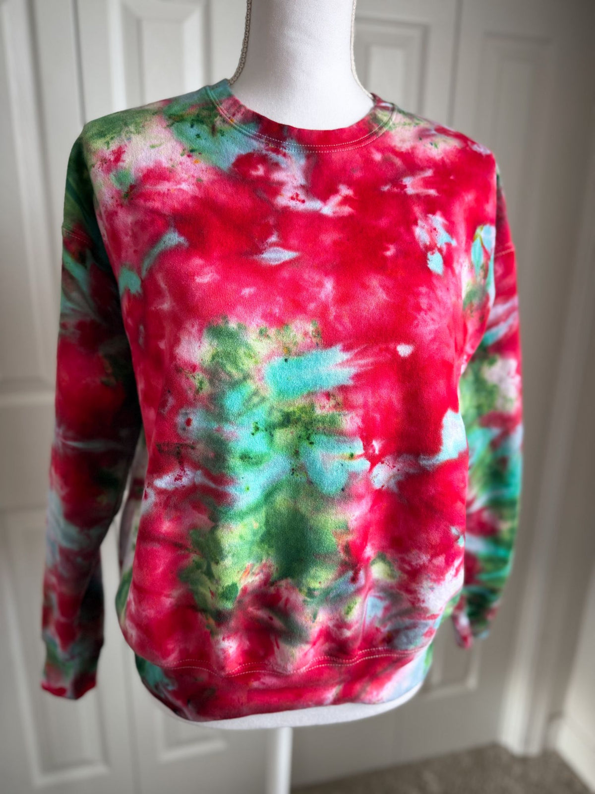 A hand ice-dyed Christmas crewneck in crimson and pine green